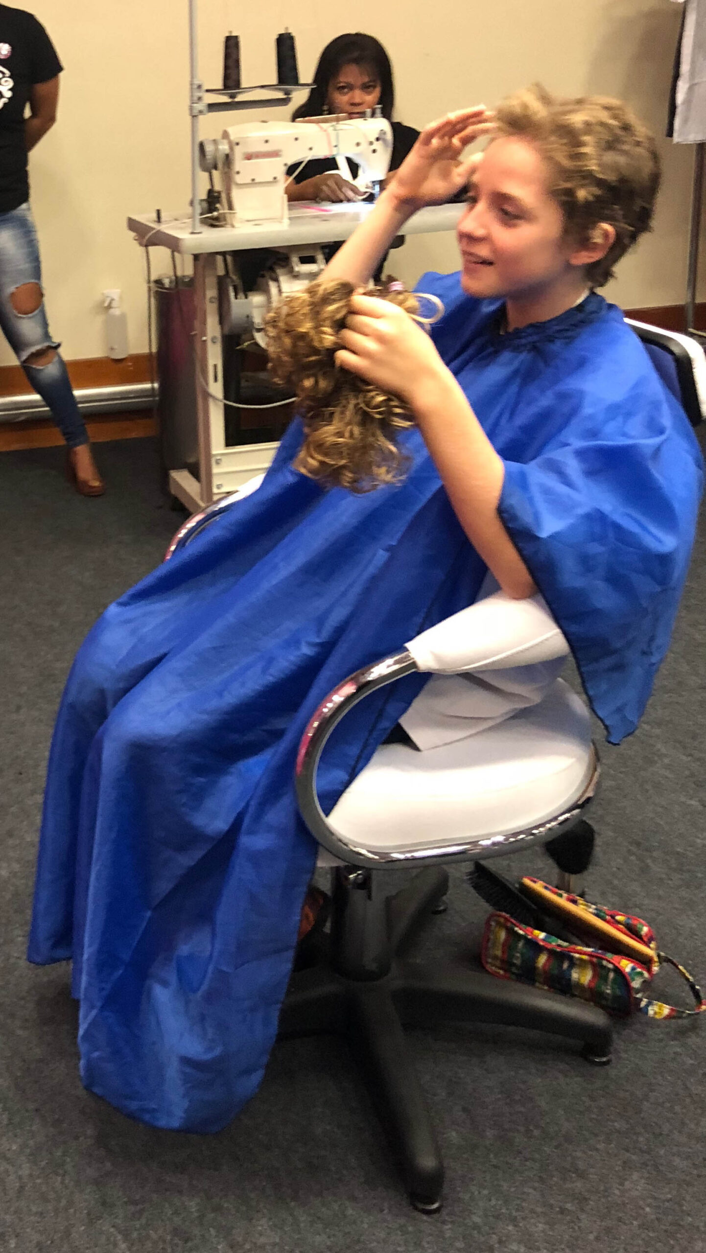 Menino alisando sua cabeça após doar cabelo para pacientes com câncer.
